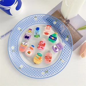 Assorted acrylic hair clips shaped like miniature beverage bottles in a decorative tray