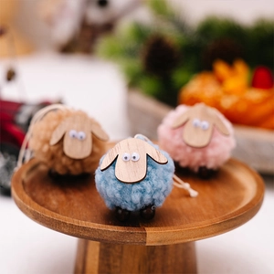 Detailed view of three colorful wool felt sheep ornaments on a rustic wooden base