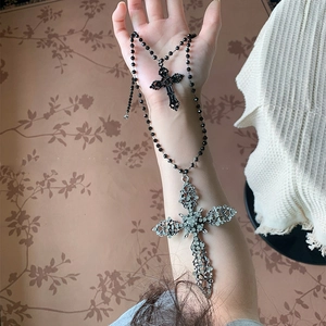 Gothic hollow cross necklace with rhinestones and black beads on woman's arm