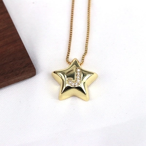 Macro shot of gold star pendant with sparkling cubic zirconia letter J on a fine chain
