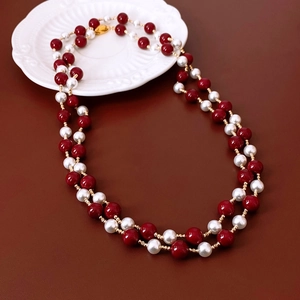 Detail of double-layer vintage red bead and pearl necklace with golden heart clasp