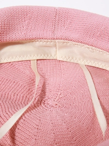 Detailed macro view of pink knitted beret interior with beige sweatband and adjustable drawstring