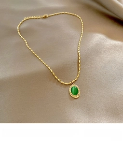 Close-up of vintage gold beaded necklace with oval green cat-eye stone pendant on satin
