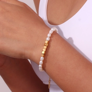 Detailed close-up of a freshwater pearl and gold square bead bracelet on a female wrist