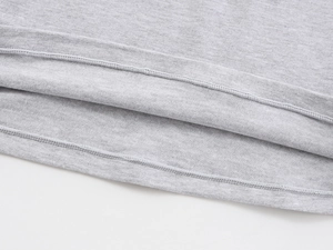 Close-up of the double-stitched hem on a grey knit shirt showing premium fabric texture