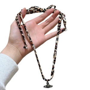 Fashionable leopard fabric ribbon necklace featuring a silver Saturn orbit pendant