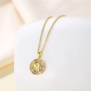 Macro shot of 18K gold-plated necklace with M letter pendant and baguette zircon stones