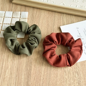 Detail of olive green and rust red ribbed knit fabric scrunchies on wooden background