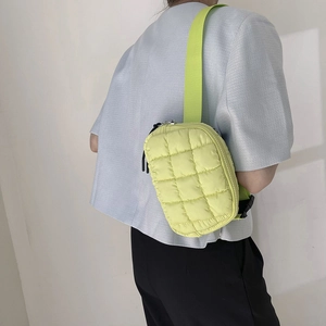 Rear view of a light green quilted nylon crossbody waist bag with wide shoulder strap