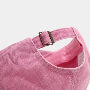 Detail of pink vintage washed cotton baseball cap featuring an adjustable brass buckle