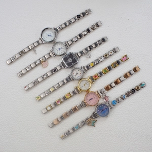 Flat lay macro of modular stainless steel charm watches with crystals and enamel pendants
