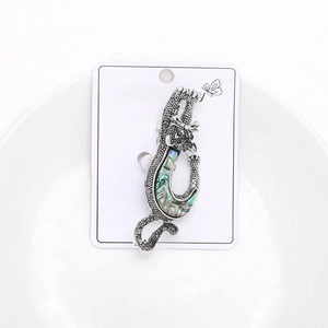 Detail view of a cat brooch featuring silver textured alloy and natural abalone shell inlay