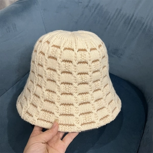 Close-up of cream knit bucket hat featuring brown stripe texture and wool yarn finish