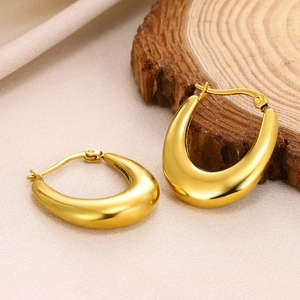 Detailed close-up of golden U-shaped waterdrop earrings on a natural wood surface