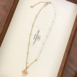 Detail of 18K gold-plated maple leaf necklace with pearls on a velvet display tray