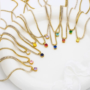 Minimalist gold birthstone necklaces with colorful round zircon pendants on a white plate