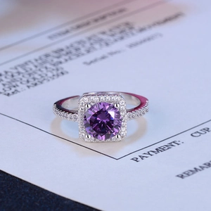 Macro detail of silver ring with purple center stone and surrounding diamond accents