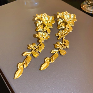 Detail of matte gold floral earrings with hanging leaf tassels and textured petals