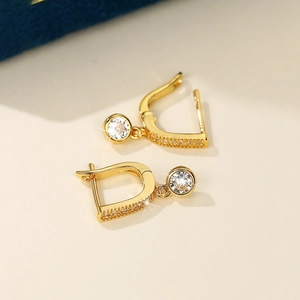 Macro detail of gold-plated D-shaped earrings with rows of pavé and a round zircon drop