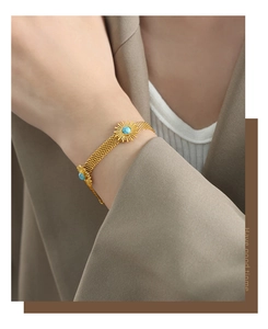 Close-up of golden sunflower bracelet with turquoise bead on a model's wrist