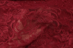Close-up of wine red floral lace fabric with intricate mesh knitting and sheer texture
