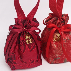 Detail of red brocade wedding favor bags with gold Double Happiness charms and ribbons