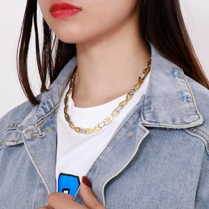 Close-up of two-tone gold and silver steel link necklace worn by a model in soft light