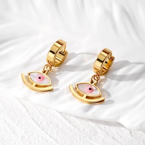 Macro detail of gold evil eye teardrop earrings with pink iris on textured pedestal