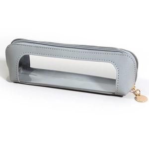 Close-up of grey leather pencil case with a transparent window and gold zipper detail