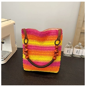 Detail of rainbow straw tote bag featuring multi-color weave and dark wooden bead handle
