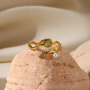 Macro detail of wave branch ring with green gemstone, white pearl and leaf accents