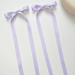 Close-up of dual purple satin ribbon bow hairpins with long streamers for ballet style