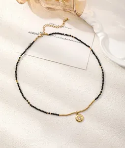 Detailed view of evil eye pendant with black spinel beads on a minimalist gold necklace