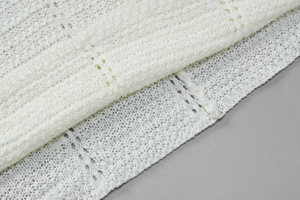 Vista macro dettagliata dell'intricato motivo a maglia traforata su un abito bianco