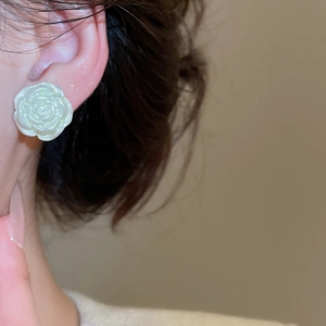 Close-up of white rose petal earrings with pearlescent finish worn by a model