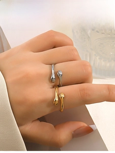 Detail of gold and silver hugging hands open rings worn on fingers with metallic finish