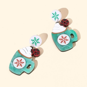 Macro view of Christmas earrings with green marbled cup, candy cane and snowflake details