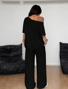 Vista trasera de un conjunto lounge negro de dos piezas para mujer con pantalón de pernera ancha