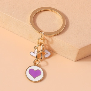 Detail of gold keychain with white enamel heart pendants and purple heart pattern