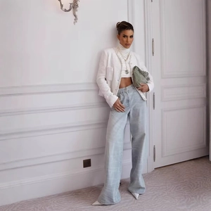Giacca elegante in tweed bianco da donna con jeans a gamba larga azzurri e decori di perle