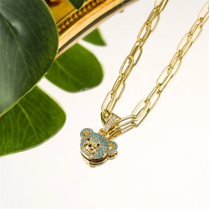 Macro shot of gold paperclip chain necklace with a blue zircon encrusted bear pendant