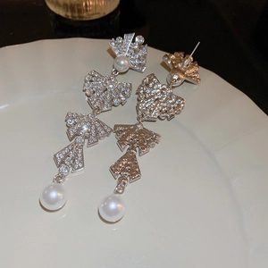 Detailed macro view of silver bow pearl tassel earrings with luxury diamond accents