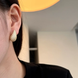 Model wearing gold teardrop earrings pave set with sparkling white cubic zirconia stones