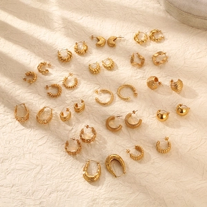 Flat lay of multiple geometric 18K gold-plated stainless steel earrings on textured surface