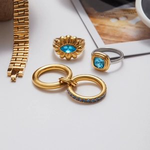 Detailed close-up of gold rings set with blue zircons and a sleek metal watch band