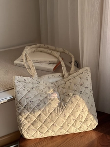 Détail d'un sac cabas en velours côtelé matelassé avec motif floral sur une chaise
