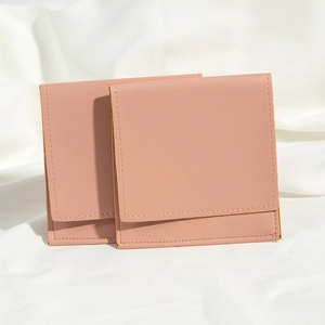 Close-up of two pink PU leather drawstring pouches for jewelry storage on white fabric