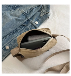 Interior capacity detail of a khaki nylon crossbody bag showing space for a smartphone