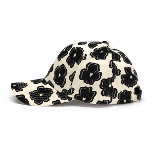 Detailed view of cream floral baseball cap featuring black flower patterns and embroidery