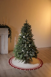 Dettaglio albero di Natale innevato con luci LED calde e tappeto bianco bordo rosso